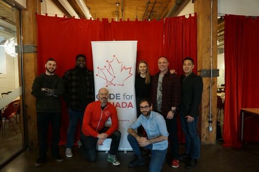 C4C Fellows and their government partners from Transport Canada in front of a Code for Canada banner during fellowship onboarding.