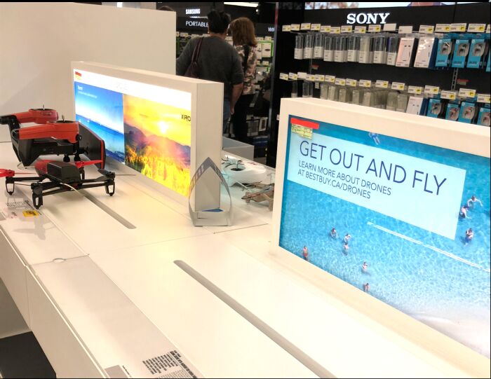 The drone sales display at a store in Toronto. A drone is seen on the table next to a screen reading “Get out and fly.”